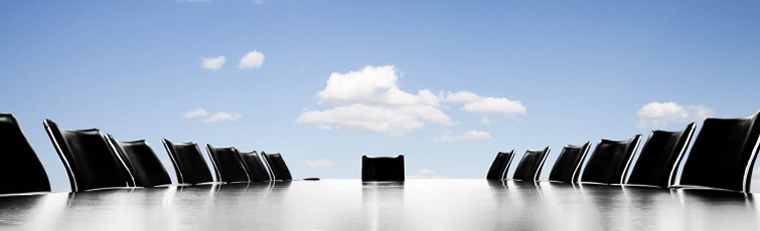 picture of empty chairs and table in a board room that appears to be open to bright open sky with clouds.