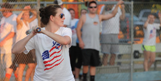 picture of adult femail swinging batting with crowd in background